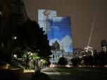 La deuxième image, prise de nuit, capte une projection sur un bâtiment.